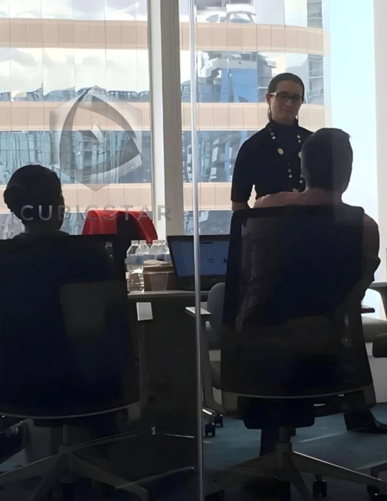Elevador accesible Sesión de consultoría sobre accesibilidad digital en una sala de reuniones de CubicStar. Una mujer de pie, vestida de negro, habla con dos personas sentadas mientras trabajan en sus computadoras. La sala tiene una pared de vidrio con vista a un edificio moderno. La imagen representa un espacio de trabajo colaborativo enfocado en la evaluación y mejora de la accesibilidad en entornos digitales.